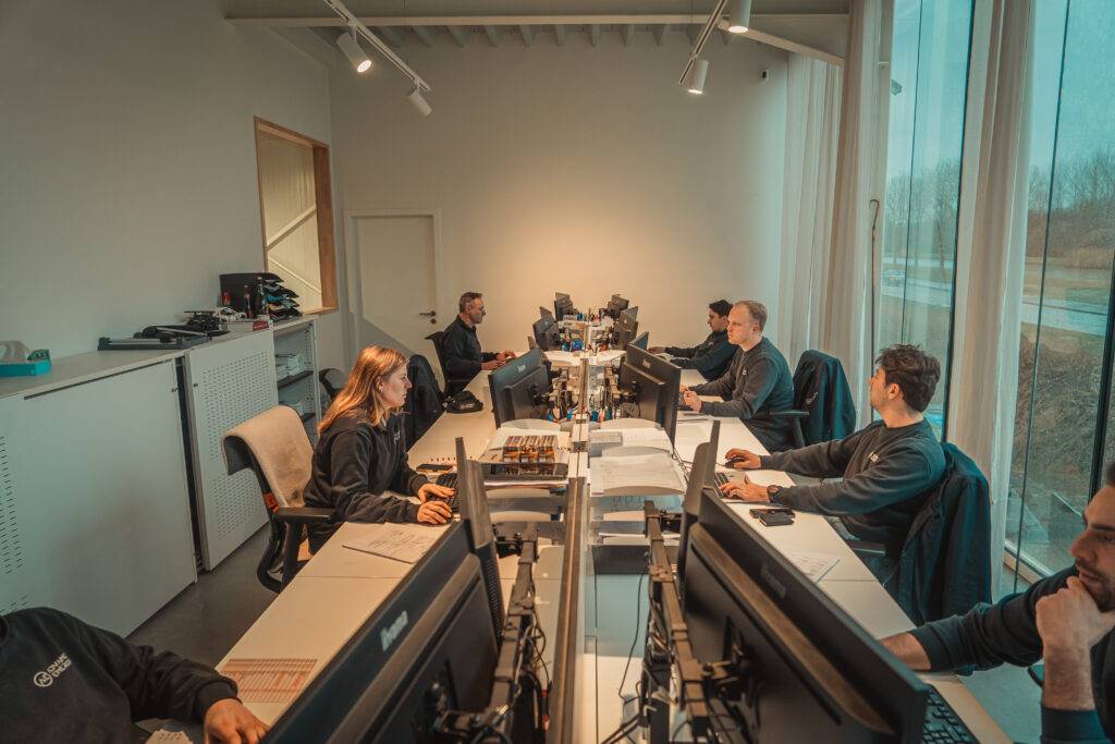 Medewerkers van Advanced Energy aan hun bureau in het kantoor, met dossiers en schermen