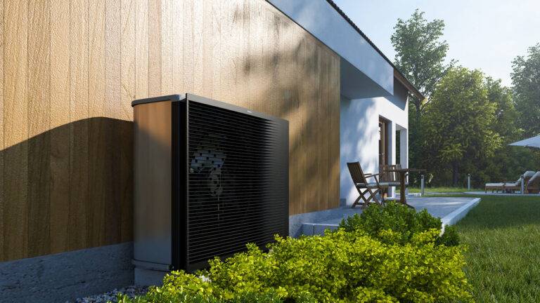 Buitenunit van een lucht-water warmtepomp naast een gerenoveerde woning, een typische ingreep om na aankoop te voldoen aan de renovatieplicht bij EPC-label E of F