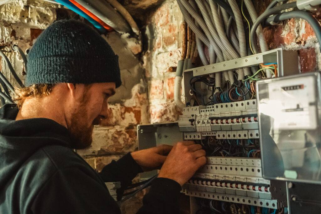 Technicus werkt aan een zekeringkast met automaten, naast de elektriciteitsmeter