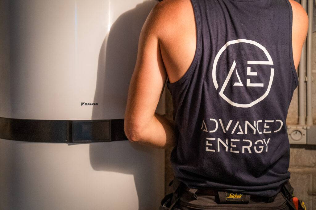 Technicus van Advanced Energy werkt aan een witte Daikin-warmtepompboiler in een technische ruimte