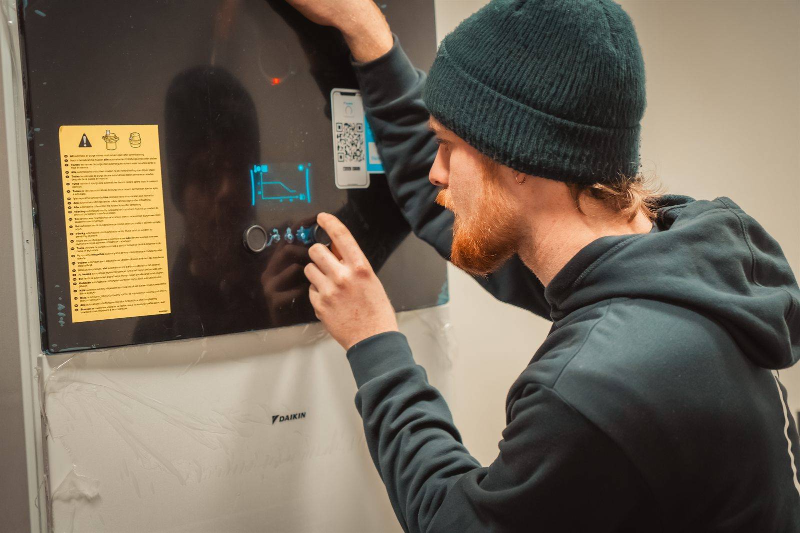 Technieker van Advanced Energy start een Daikin-warmtepomp op; het toestel is nog afgedekt met beschermfolie